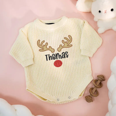 Baby romper with deer antlers and 'Thomas' text on a pink background
