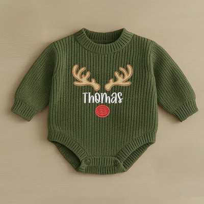 Green baby onesie with deer antlers and 'Thomas' text on a beige background