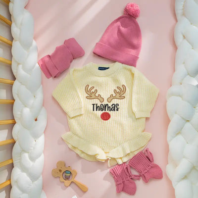 Baby outfit with yellow romper, pink hat, and socks on a pink background