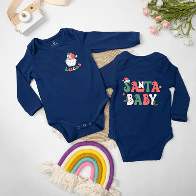 Two navy blue baby onesies with Christmas-themed designs on a light background.