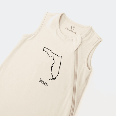 Beige sleeveless baby romper with 'Jackson' design on a light gray background