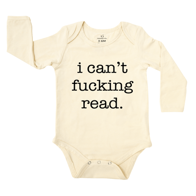 Beige baby onesie with black text 'i can't fucking read' on a white background