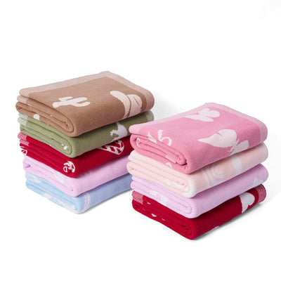 Stack of folded jacquard knit baby blankets in various colors on a white background