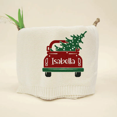 Cream personalized baby blanket with a red truck and Christmas tree design on a beige background