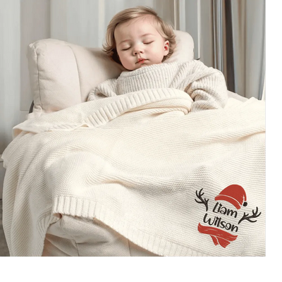 Child sleeping under a cream custom baby blanket with personalized design, sitting on a couch.
