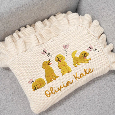 Cream personalized baby blanket with embroidered golden retrievers and 'Olivia Kate' text on a gray surface
