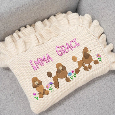 Cream personalized baby blanket with embroidered poodles and 'Emma Grace' text on a gray surface