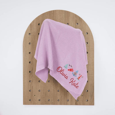 Lilac personalized baby blanket with embroidered name and nautical designs on a wooden board