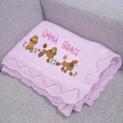 Lilac personalized baby blanket with embroidered poodles and 'Emma Grace' text on a gray surface