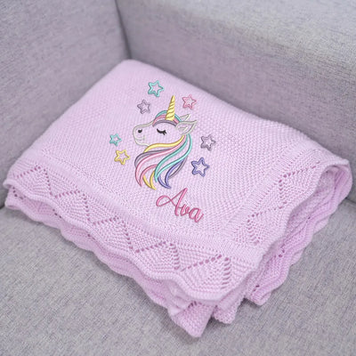 Lilac personalized baby blanket with unicorn design and name 'Ava' on a gray surface