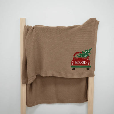 Mocha personalized baby blanket with a red truck and Christmas tree design on a wooden ladder against a white background