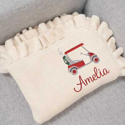 Personalized baby blanket with a golf cart design and the name 'Amelia' on a gray surface.
